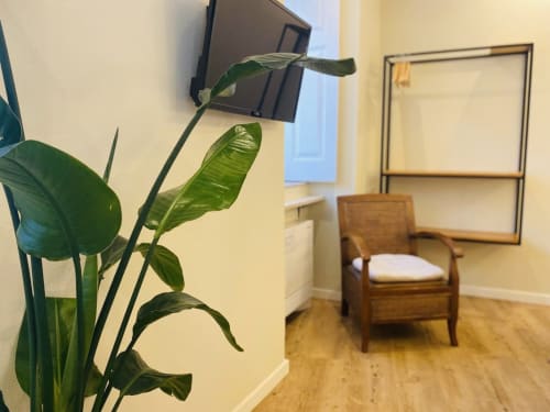 Área de estar iluminada na Pousada Histórica Santa Cruz em Lagos, com planta em vaso verde, cadeira de madeira e TV de tela plana