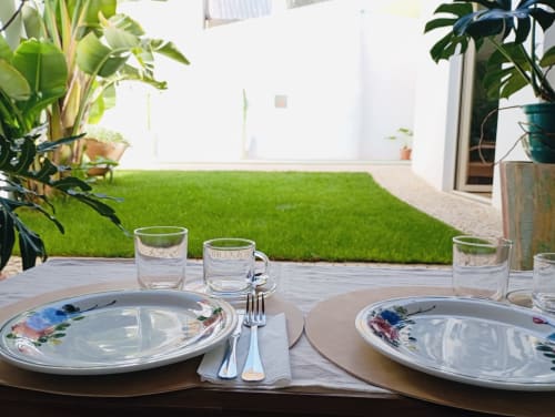 Elegante espaço de refeições ao ar livre na Santa Cruz Historic Guest House em Lagos com talheres, copos e jardim impecável