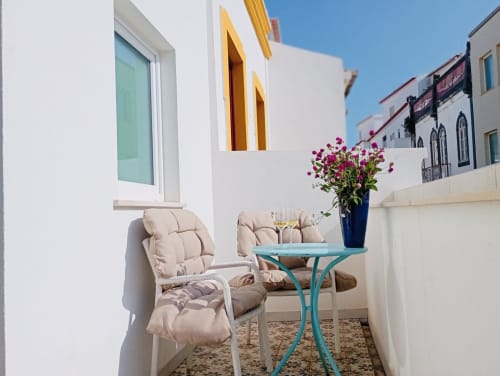 Terraço ensolarado com cadeira estofada e mesa turquesa na Santa Cruz Historic Guest House, Lagos Portugal