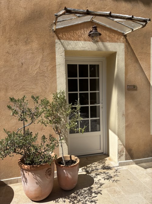 Entrée de maison d'hôtes provençale avec pots en terre cuite, oliviers et marquise métallique à Rochegude, Drôme
