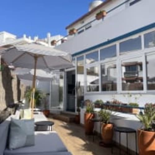 Vila Alexandra hostel terrace in Costa da Caparica with white umbrellas, lounge seating, and potted plants overlooking the