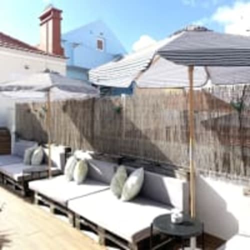 Rooftop seating area at Vila Alexandra hostel in Costa da Caparica with loungers, umbrellas, and coastal views