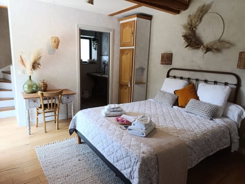 Bright bedroom at Le Petit Bégou B&B with metal bed frame, white bedding, wooden desk, and garden view windows in