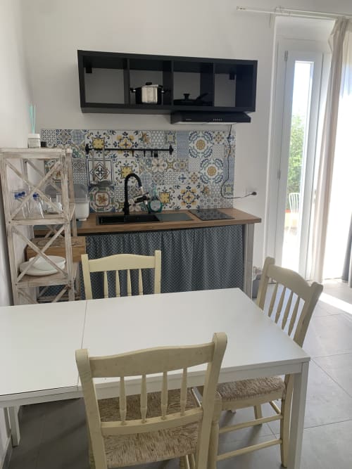 Luminosa cucina moderna e zona pranzo nell'appartamento Ca' Salino con rivestimento in piastrelle geometriche, tavolo bianco e vista sul giardino