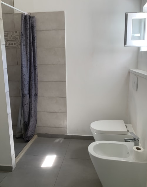 Bagno moderno dell'appartamento Innamorati di Ca' Salino con doccia a filo pavimento, wc, bidet e sanitari bianchi