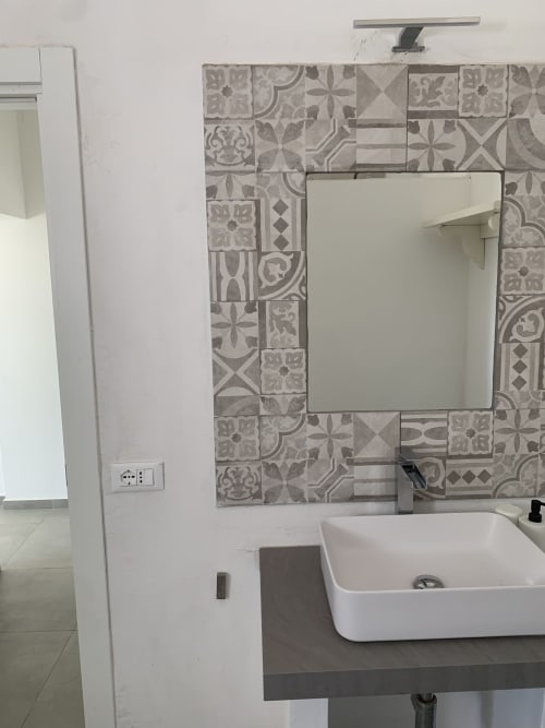 Bagno moderno nell'appartamento Ca' Salino con lavabo a vessel bianco, piastrelle decorate e specchio nella camera Innamorati