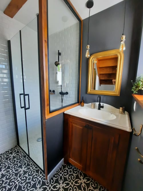 Salle de bains moderne au Petit Bégou avec meuble en bois, lavabo blanc, miroir doré et douche à l'italienne