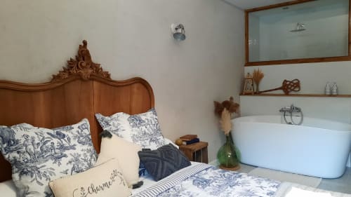 Chambre du Petit Bégou avec lit en bois ouvragé, literie bleue et blanche, baignoire attenante à Saint-Auban-d'Oze