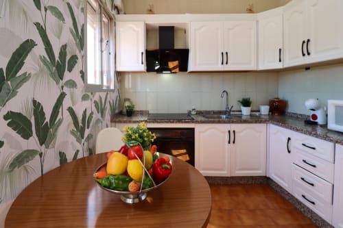 Cocina moderna con gabinetes blancos, encimeras de granito y mesa de comedor con frutas frescas en la cabaña La Casa de Tita Clota