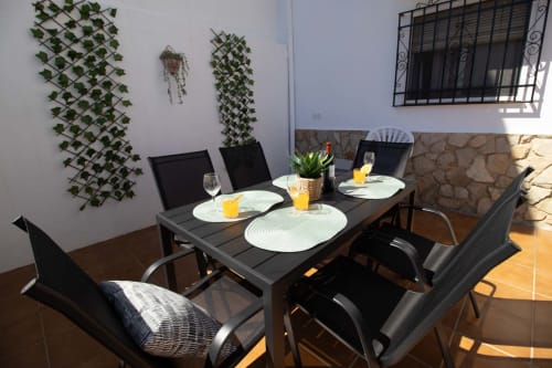 Terraza de comedor al aire libre en La Casa de Tita Clota en Setenil de las Bodegas con mesa preparada, sillas negras e hiedra trepadora