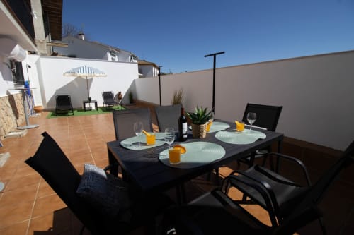 Comedor en terraza de la cabaña La Casa de Tita Clota en Setenil de las Bodegas con mesa servida y tumbonas
