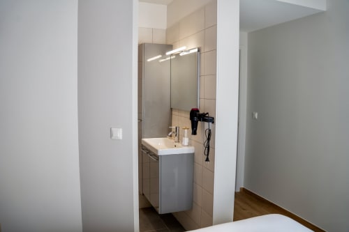 Salle de bain moderne avec lavabo, miroir et murs carrelés dans l'appartement Japandi de la Suite Le 1 Péraudel à Castres
