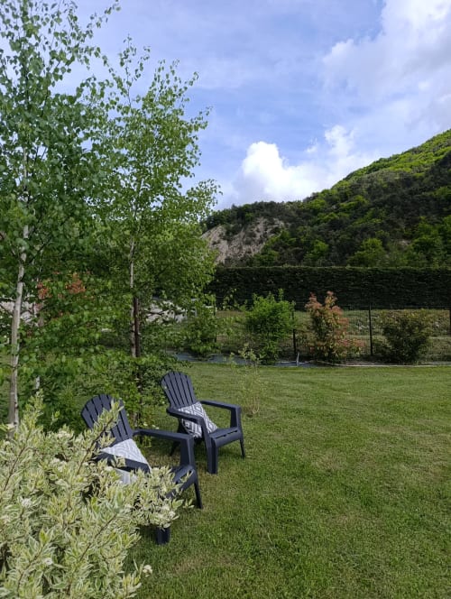 Deux chaises Adirondack noires dans le jardin de La Bergerie de Roger à Saint-Auban-d'Oze, avec pelouse verte et bouleaux