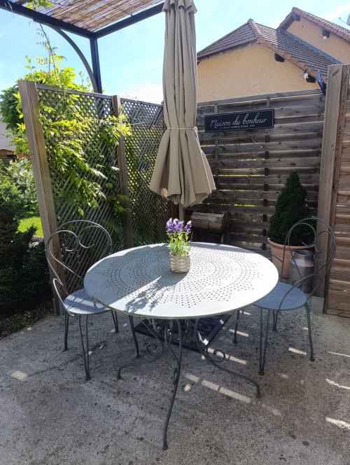 Espace de restauration extérieure au Petit Bégou avec table ronde, chaises et parasol dans un jardin
