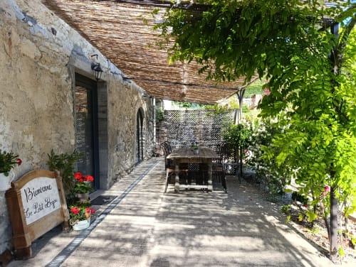 Charmante terrasse du Petit Bégou avec table à manger, murs de lierre et pierre rustique à Saint-Auban-d'Oze