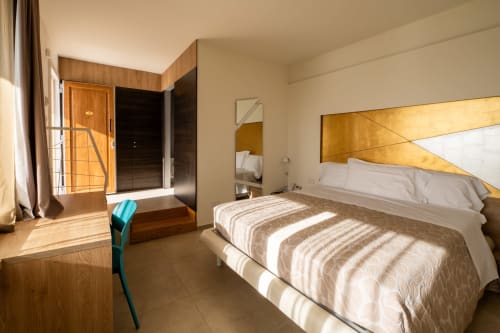 Deluxe Standard room at Hotel Belvedere Resort with sea view balcony, modern bed, and warm wood accents.