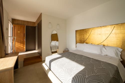 Hotel Belvedere Resort deluxe room with sea view, featuring queen bed with gold headboard, wooden furnishings, and modern