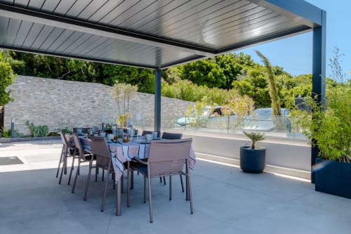 Modern villa dining terrace with sea views in Saint-Florent, featuring covered pergola, outdoor table and Mediterranean