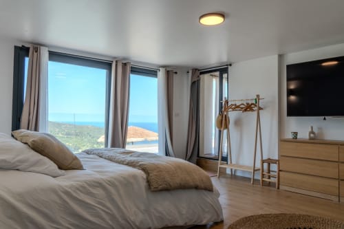 Luxury bedroom at Villa Roya in Saint-Florent with sea view, modern furnishings, and panoramic windows overlooking the coast