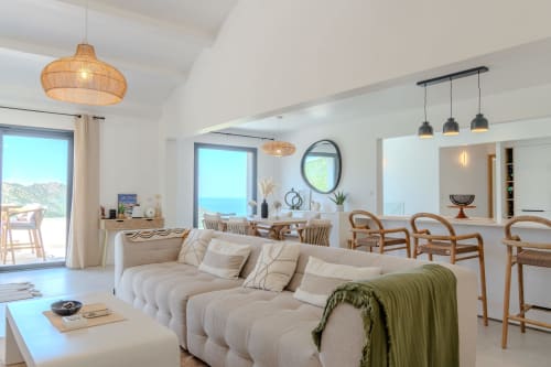 Spacious villa living room with sea view at Villa Roya, Saint-Florent, featuring cream sofa, woven pendant lights, and modern
