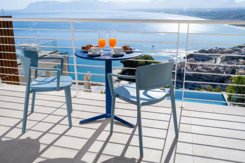 Seaside balcony at Hotel Belvedere Resort with blue table, two chairs, orange juice, and panoramic Mediterranean sea view