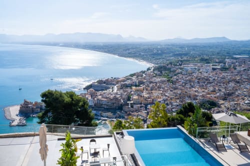 Luxury poolside terrace at Hotel Belvedere Resort overlooking Castellammare del Golfo's coastal town and Mediterranean Sea