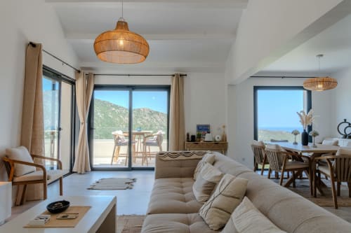 Villa Roya living room with sea views, beige sofa, wooden furniture and modern pendant lights in Saint-Florent