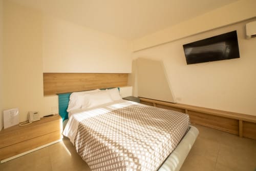 Modern bedroom at Hotel Belvedere Resort with double bed, wooden headboard, and flat-screen TV in Castellammare del Golfo