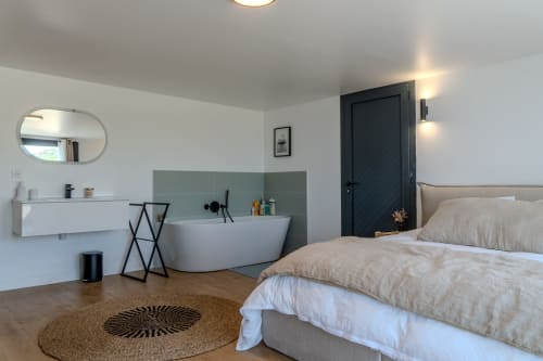Modern villa bedroom with en-suite bathroom at Villa Roya in Saint-Florent, featuring bed, bathtub, and sea view