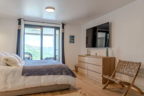 Bright modern bedroom at Villa Roya in Saint-Florent with sea view balcony, wooden furniture, and contemporary decor