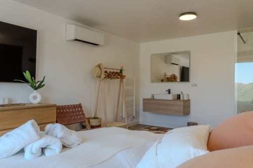 Modern villa bedroom at Villa Roya, Saint-Florent with sea view, wooden furnishings, en-suite bathroom, and air conditioning