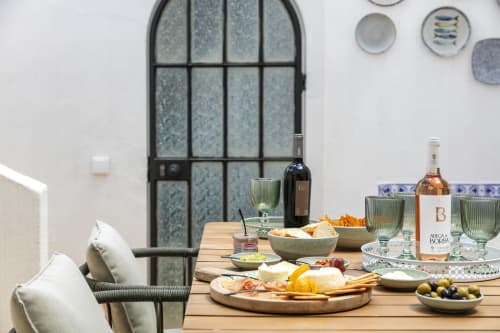Outdoor dining table at Villa Colina in Carvoeiro with wine, cheese board, snacks, and glasses overlooking the pool area