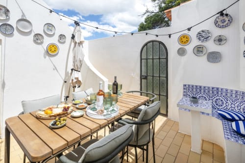 Outdoor dining patio at Villa Colina in Carvoeiro with wooden table, decorative plates on white walls, and private pool area