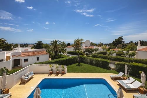 Villa Colina private pool with sunny patio, manicured lawn, and surrounding white villas in Carvoeiro