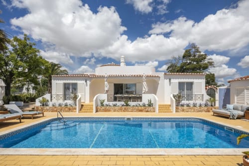 Villa Colina in Carvoeiro featuring a private pool, white Mediterranean-style villa, terrace with loungers, and blue sky
