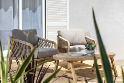 Modern outdoor patio seating at Villa Colina in Carvoeiro with wooden chairs, cushions, and a round table with potted plants