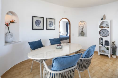 Modern dining area in Villa Colina, Carvoeiro with marble table, blue cushioned chairs, wall art, mirror, and shelving