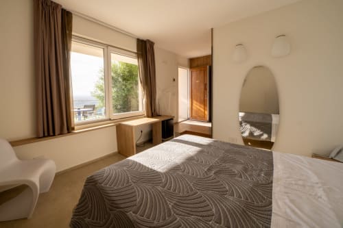 Belvedere Resort deluxe room with sea view, featuring patterned bed, wooden desk, and balcony overlooking Castellammare del