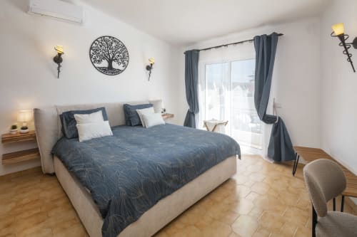 Modern bedroom in Villa Colina, Carvoeiro with blue bedding, terrace access, and sea views