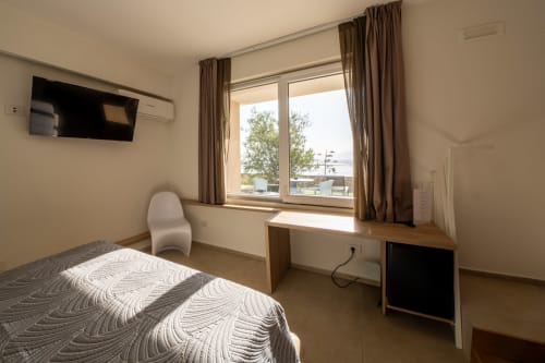 Deluxe Standard room with sea view at Hotel Belvedere Resort, featuring bed, desk, flat-screen TV, and window overlooking