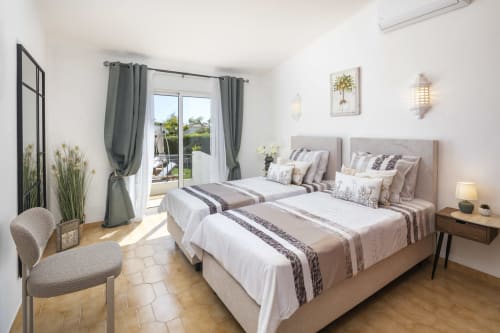 Twin beds in bright villa bedroom at MarVillas Rentals Carvoeiro with patio doors, green curtains, and modern furnishings
