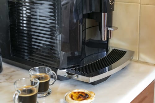 Automatic espresso machine with two cups of coffee and pastry on marble countertop at Villa Colina, Carvoeiro