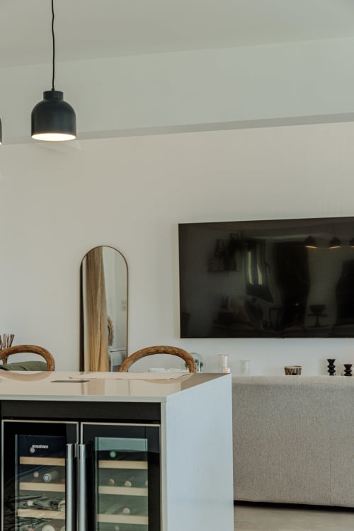Modern villa kitchen at Villa Roya with black pendant light, wine cooler, and white countertop overlooking Saint-Florent