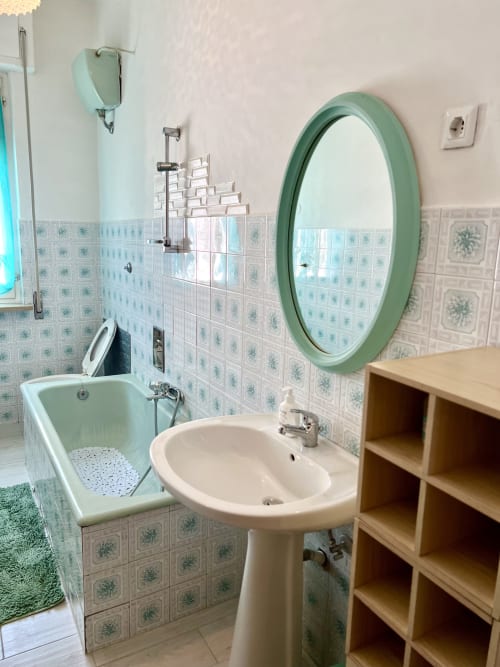 Bagno dell'appartamento Casa Nicola a WelcHome, San Vito Chietino con lavabo su colonna, specchio rotondo verde e vasca da bagno