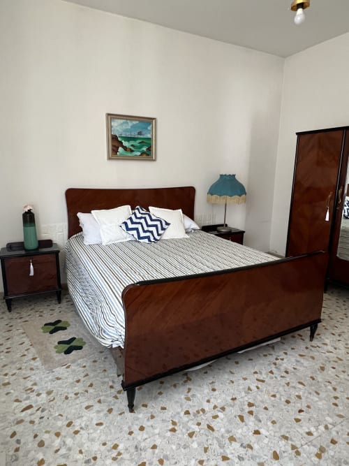 Camera da letto in Casa Nicola, San Vito Chietino con letto in legno, biancheria a righe e pavimento in cotto