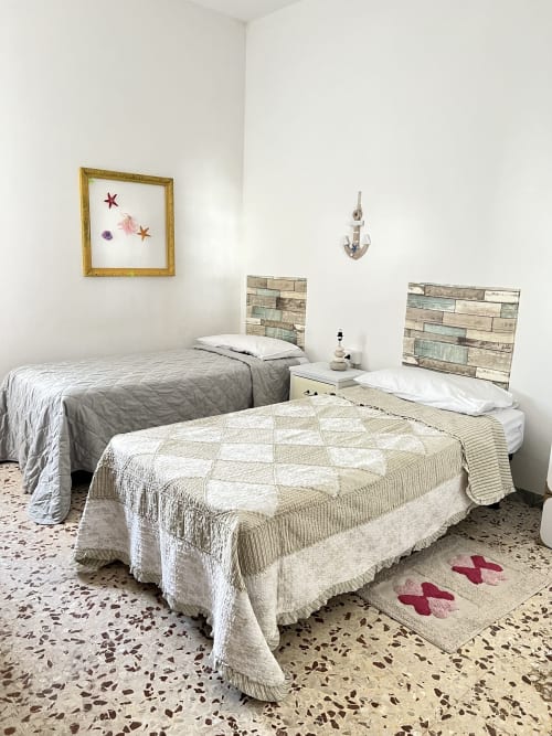 Due letti con trapunte crema e beige nell'appartamento Casa Nicola, San Vito Chietino, con testiere in legno e decorazioni nautiche