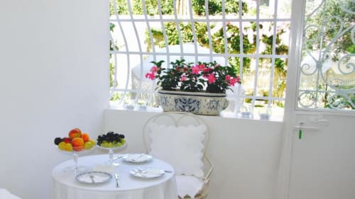 Elegante colazione al Relais Palazzo Cacace con fiori rosa, frutta fresca, biancheria bianca e vista sul giardino