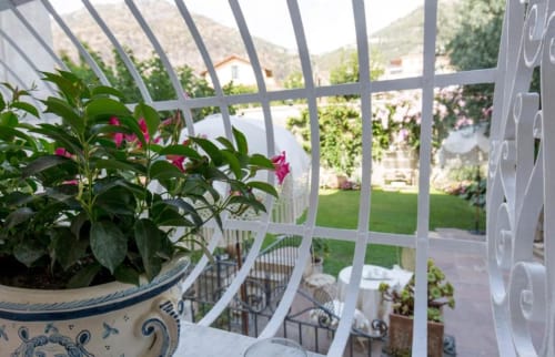 Balcone con pianta fiorita, pergolato bianco e vista sul lussureggiante giardino di Relais Palazzo Cacace, Meta di Sorrento