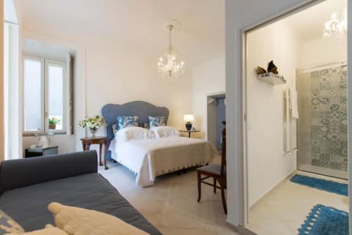 Lussuosa camera tripla presso Relais Palazzo Cacace a Meta di Sorrento con letto dalla testata blu, lampadario e bagno ensuite