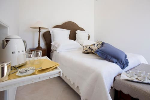 Camera Deluxe Anthea al Relais Palazzo Cacace con letto bianco, testata in legno, bollitore e biancheria blu a Meta di Sorrento